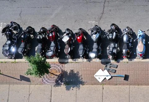 Aerial view of motorcycles of all regular types neatly parked in a row by the Stock Photos