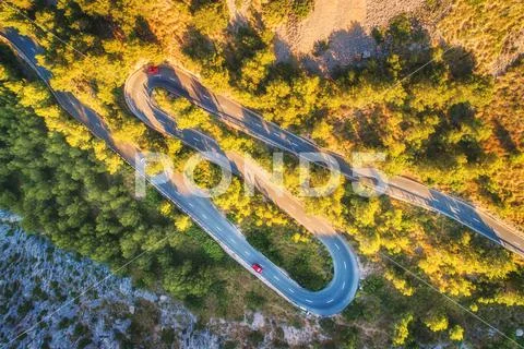 Aerial view of mountain curve road with cars, green forest Stock Photos