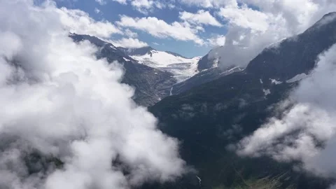 Aerial view of a mountain glacier through fluffy clouds Stock Footage 317656096