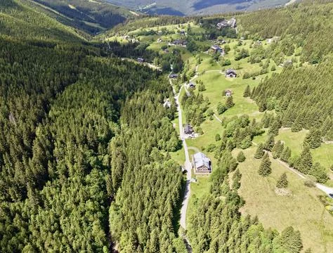 Aerial view of mountain hamlet surrounded by dense conifer forest Stock Photos