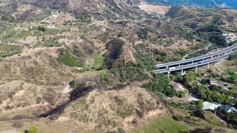 Aerial view of mountain highway bridge over plain near distant dam Stock Footage 343962398
