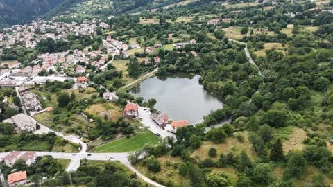 Aerial view of a mountain lake surrounded by green trees and houses 库存影片 341732676