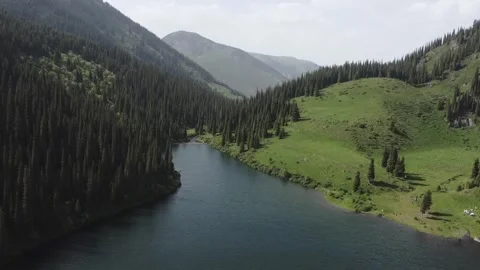 Aerial view of mountain lake in valley with green meadows at Kolsay Lakes Stock Footage 345410341