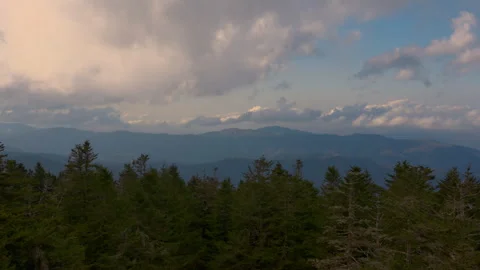 Aerial view of mountain landscape with dramatic clouds drifting across blue sky Stock Footage 321666476