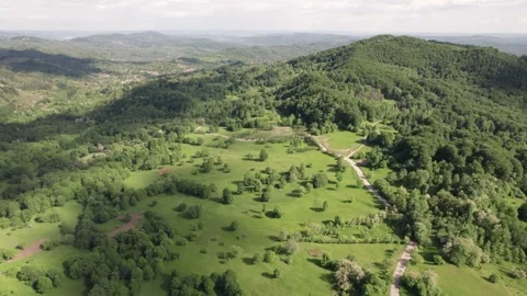 Aerial view of a mountain meadow over forests and a distant village in Romania Stock Footage 336493380