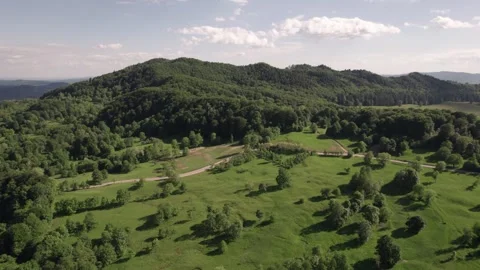 Aerial view of a mountain meadow over forests and a distant village in Romania Stockbeeldmateriaal 336493457