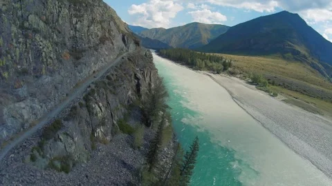 Aerial view of a mountain path along a cliff along a stormy river Stock Footage 284923139