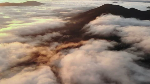  Aerial view of a mountain peak surrounded by morning fog and glowing clouds dur Stock Footage 297005167