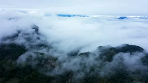 Aerial view of mountain peaks emerging from a dense sea of rolling clouds Video stock 342333975