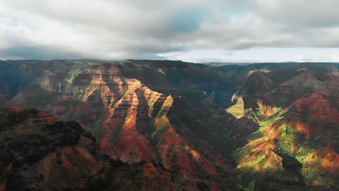 Aerial view of a mountain range with green slopes under a cloudy sky in Kauai Vídeo Stock 138238009