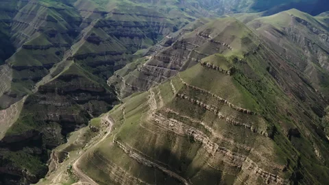 Aerial view of a mountain range with lush slopes, terraced fields, and snaking Video stock 265916855