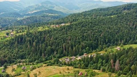 Aerial view of mountain range, road, and fir forest with village houses. Stock Footage 120277034