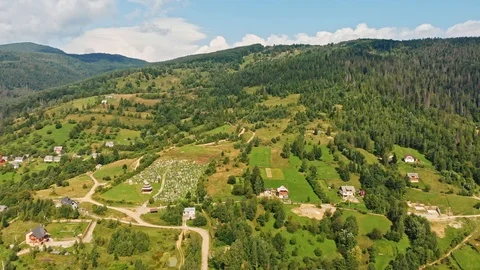 Aerial view of mountain range, road, and fir forest with village on background. Stock Footage 120277052