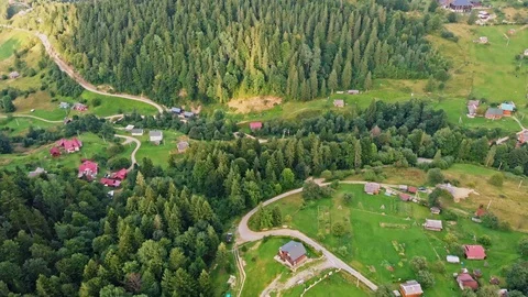 Aerial view of mountain range, road, and fir forest with village Stock Footage 121926645