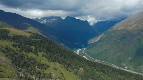 Aerial view of a mountain river flowing through a valley under snow-capped Stock Footage 160928526