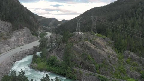 Aerial view of a mountain river with high tension power lines next to the sea to Stock Footage 135849065