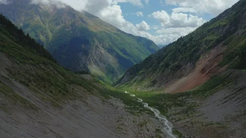 Aerial view of a mountain stream flowing between cloud-covered mountain peaks. Stock Footage 236200420