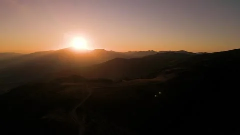 Aerial View of Mountain Sunset Over Silhouetted Peaks and Ridge Road Stock Footage 345159256