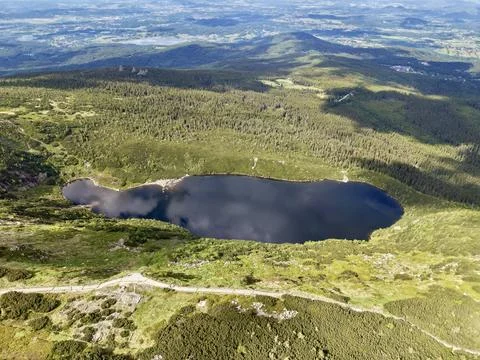 Aerial view of a mountain tarn surrounded by alpine forest and meadows Stock Photos