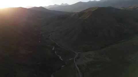 Aerial view of a mountain valley with sun flare at sunset, Kyrgyzstan Видео 347240053