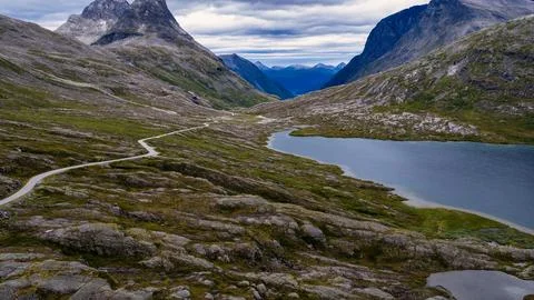 Aerial view of mountain valley with winding road and alpine lake, Rauma Norwa Foto stock
