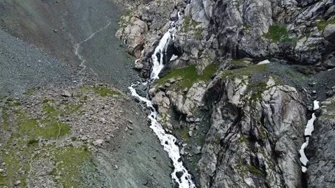 Aerial view of mountain waterfall cascading through gorge with hiking trail Vídeos de archivo 335093563