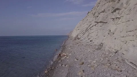 Aerial view moving along the cliffs near the sea above stones at the beach 스톡 동영상 86902600