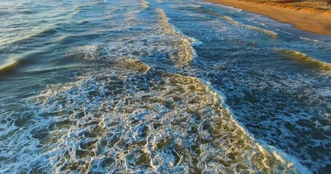 Aerial view moving backwards above emerald color wavy sea illuminated by sun Stock Footage 128576779
