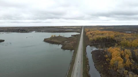 Aerial view moving forward above a paved road that is cutting through farmland  Stock Footage 255669477