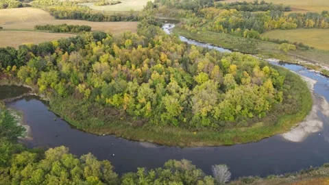 Aerial view moving forward over a winding rocky river that runs through farm  Stock Footage 273318352