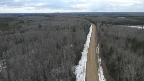 Aerial view moving forward over a gravel road that winds through a forest Stock Footage 273491056
