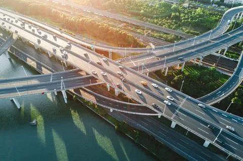 Aerial view of multiple highways intersect above a calm river, surrounded by Stock Photos