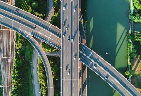 Aerial view of multiple highways intersect above a calm river, surrounded by Stock Photos