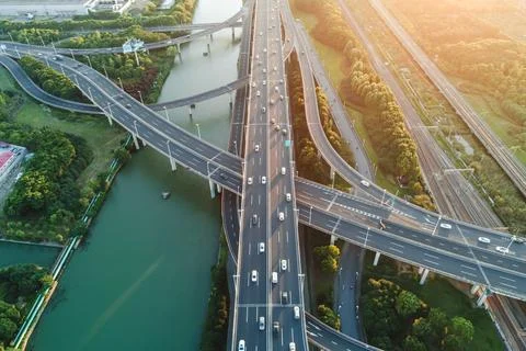 Aerial view of multiple highways intersect above a calm river, surrounded by Stock Photos