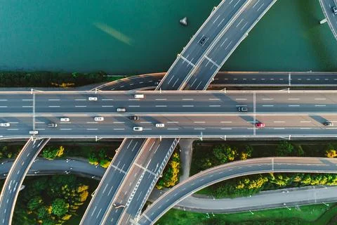 Aerial view of multiple highways intersect above a calm river, surrounded by Stock Photos