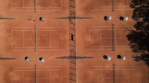 Aerial view of multiple red clay tennis courts with nets and umbrellas, captured Video stock 316845018