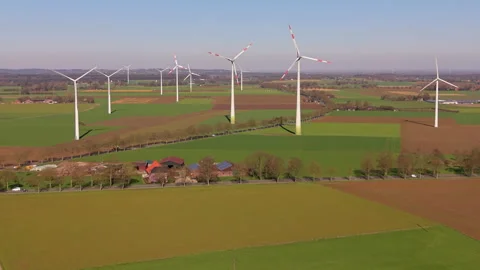 Aerial view of multiple wind turbines standing in green agricultural fields. 스톡 동영상 337563422