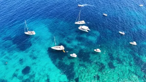 Aerial view of multiple yachts sailing in clear blue water. Vibrant sea colors Stockbeeldmateriaal 344408741