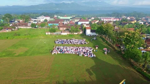 Aerial view of Muslims performing Eid al-Fitr prayer on a green field, 스톡 동영상 332627855