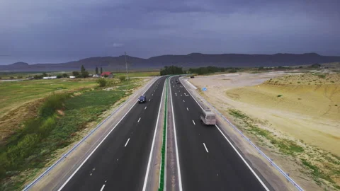 Aerial view of nearly empty highway leading toward a dark cloud bank in Stock Footage 343910821