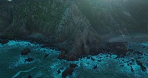 Aerial view of ocean blue waves breaking on a rocky mountain. Drone flies over Stock Footage 231681765