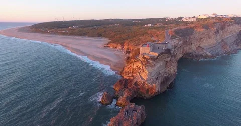 Aerial view of ocean, north Beach and Nazare lighthouse at sunset, Portugal Stock Footage 77328748