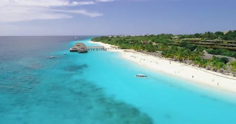 Aerial view of ocean, sandy beach, wooden hotel, swimming people Stock Footage 222995743