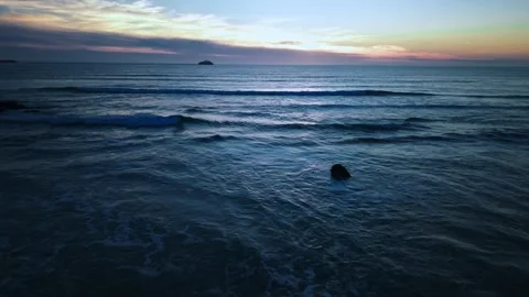 Aerial view of ocean sunset with distant island and calm waves Stock Footage 331194074