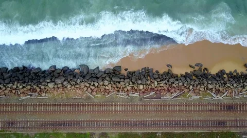 Aerial view of ocean wave reaching coastline with train moving on railway track Stock-Footage 124406990