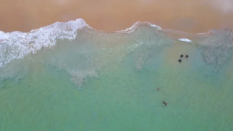 Aerial view of ocean wave reaching the coastline with tourists playing in water Stock-Footage 170831729