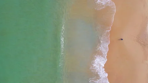 Aerial view of ocean wave reaching the coastline with a man fishing Stock-Footage 170833268