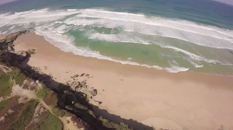 Aerial view of ocean waves along a beach and cliffside - Portugal Stock Footage 64648002