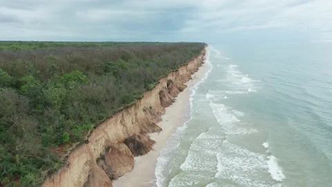 Aerial view of ocean waves beating against a rocky shore on a wooded tropical Stock Footage 156053510
