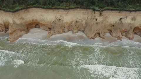 Aerial view of ocean waves beating against a rocky shore on a wooded tropical Stock Footage 156128563